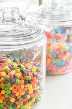 three glass jars filled with different colored candy