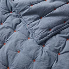 an unmade bed with blue sheets and orange stars on it