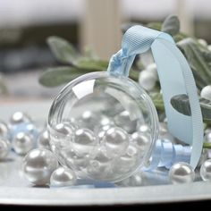 a glass ornament sitting on top of a table next to white balls and greenery