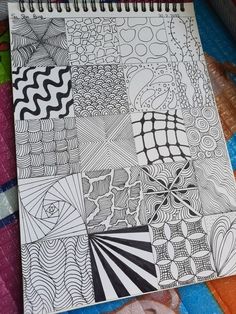 a spiral notebook with black and white doodles on the cover, sitting on top of colorful papers