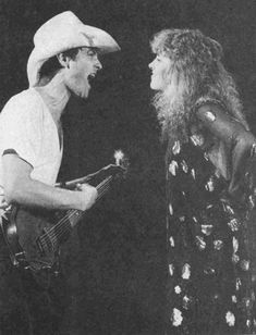 an old photo of a man and woman in costume talking to each other while holding guitars