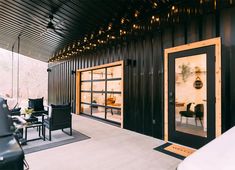 an outdoor living area with black furniture and lights on the ceiling, along with large sliding glass doors