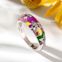 This beautifully detailed ring boasts charming flowers in bright shades of multicolored enamel. The intricate flawless enamel work coupled with white stones, make this an eye-catching piece. Inspired by the serene beauty of nature, this ring will brighten up even the dullest of days in your life. With a myriad of colours everywhere, why not add some to your jewelry box with beautiful enamel jewelry.Carat Weight: 0.216 ctStone Size: 1.4,1.2 mmStone Type: Jeulia® StoneNumber of Stones: 12 Stone Shape: RoundStone Color: Diamond WhiteWeight: 4.78 gWidth: 19.75 mmHeight: 22.29 mmThickness: 1.36 mmMaterial: Plating Color: Multicolor Flower Ring For Wedding, Multicolor Flower-shaped Wedding Rings, Green Enamel Ring For Wedding, Green Enamel Wedding Ring, Multicolor Flower-shaped Anniversary Rings, Wedding Green Enamel Ring, Multicolor Enamel Anniversary Ring, Enamel Flower Ring For Wedding, Flower Shaped Enamel Wedding Rings