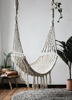 a white hammock hanging from the ceiling in a room with potted plants