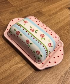 a cake sitting on top of a pink tray with polka dots and roses painted on it