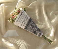 a book laying on top of a bed covered in white sheets with flowers next to it