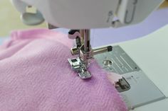 the sewing machine is working on the pink fabric