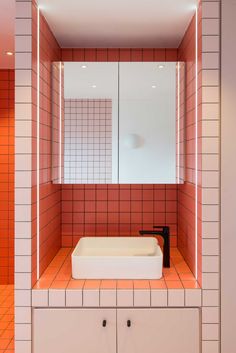 a bathroom with red and white tiles on the walls, sink and mirror in it