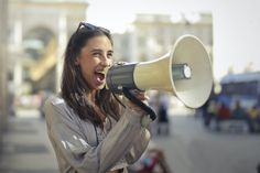 a woman holding a megaphone with the words the impact of words in front of her