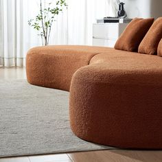 a large brown couch sitting on top of a wooden floor next to a white rug