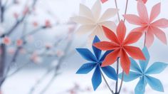 three red, white and blue paper flowers in front of a tree with snow on the ground