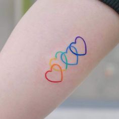 a woman's arm with three hearts painted on it and the word love spelled in rainbow colors