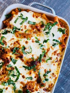 a casserole dish with cheese, spinach and sauce in it on a wooden table