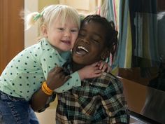 a young child is hugging an older person in front of a mirror with his mouth open