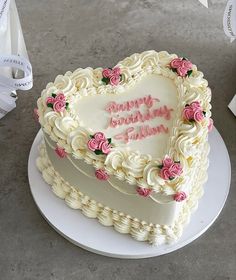 a heart shaped birthday cake with pink flowers on the top and happy birthday written in frosting