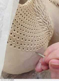 a person working on a clay sculpture with a crochet stitching pattern around it