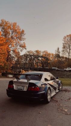 a black and white sports car parked on the side of the road in front of a bridge