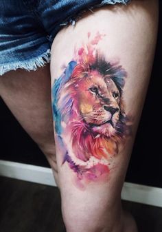 a woman's thigh with a watercolor tattoo of a lion on the side