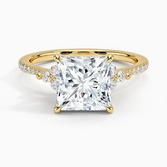 a princess cut diamond ring with two rows of diamonds on the band and shoulders, set in 18k yellow gold