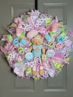 a wreath with a teddy bear and other items hanging from it's front door