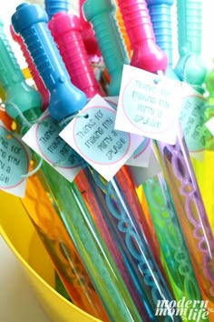 there are many different colored toothbrushes in the yellow cup with tags on them