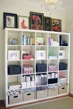 a white bookcase filled with lots of books next to a wall mounted chandelier