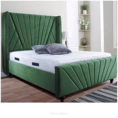 a green bed with pillows on top of it and a rug in front of it