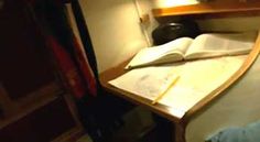 an open book sitting on top of a wooden table next to a lamp and bookshelf