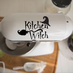 a kitchen witch sticker on the side of a blender next to a potted plant