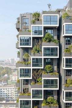 an apartment building with many windows and plants on the balconies