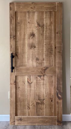 an old wooden door with black hardware on the front and side panels, in a room