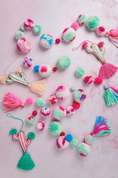 various pom poms and tassels laid out on a pink surface