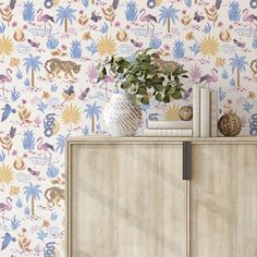 a vase with flowers on top of a wooden cabinet next to a wallpapered background