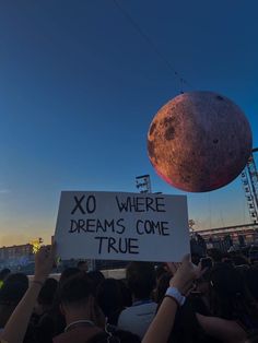 a person holding up a sign that says xo where dreams come true at sunset