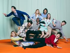 a group of people are posing on an orange sheet with their arms in the air