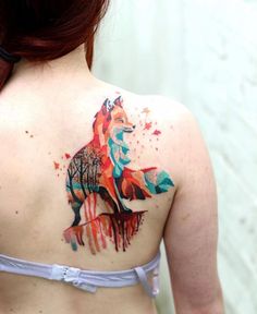 a woman with a colorful tattoo on her upper back shoulder and the image of a fox