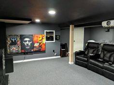 a home theater with two recliners in the middle and posters on the wall