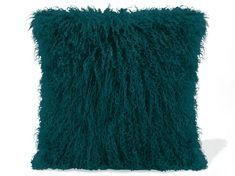 a dark green pillow with fluffy fur on the front and back side, sitting on a white surface