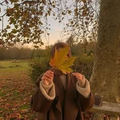 a person with a leaf on their head is standing in front of a tree and bench