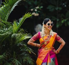 a woman in an orange and pink sari with her hands on her hips posing for the camera