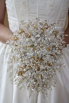 a bridal holding a wedding bouquet in her hands with pearls and golds on it