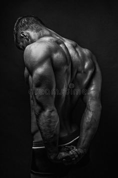 a man with his back turned to the camera, looking down at his shirtless torso