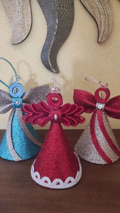 three christmas hats with bows on them sitting on top of a wooden table next to wall hangings