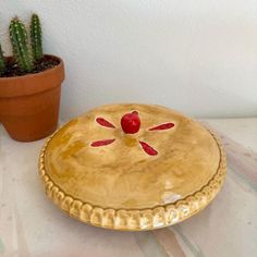 a gold plate sitting on top of a table next to a potted cactus