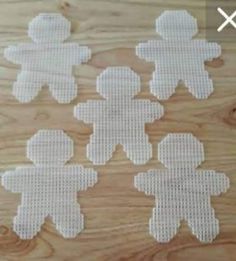 six white cross stitched teddy bears on a wooden surface with holes in the middle