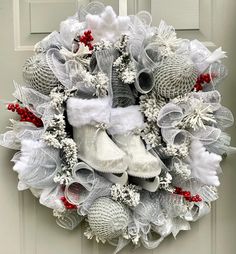 a christmas wreath with white shoes and red berries on the front door, decorated with mesh netting