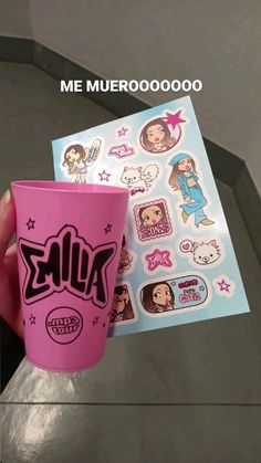 someone holding up a pink cup with stickers on it