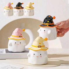 three ceramic snowmen with hats on their heads and one wearing a witches hat, while the other is holding a cell phone