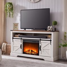 a flat screen tv sitting on top of a white entertainment center next to a fire place