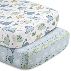 two sheets with dinosaurs on them are sitting next to each other, one is blue and the other is green